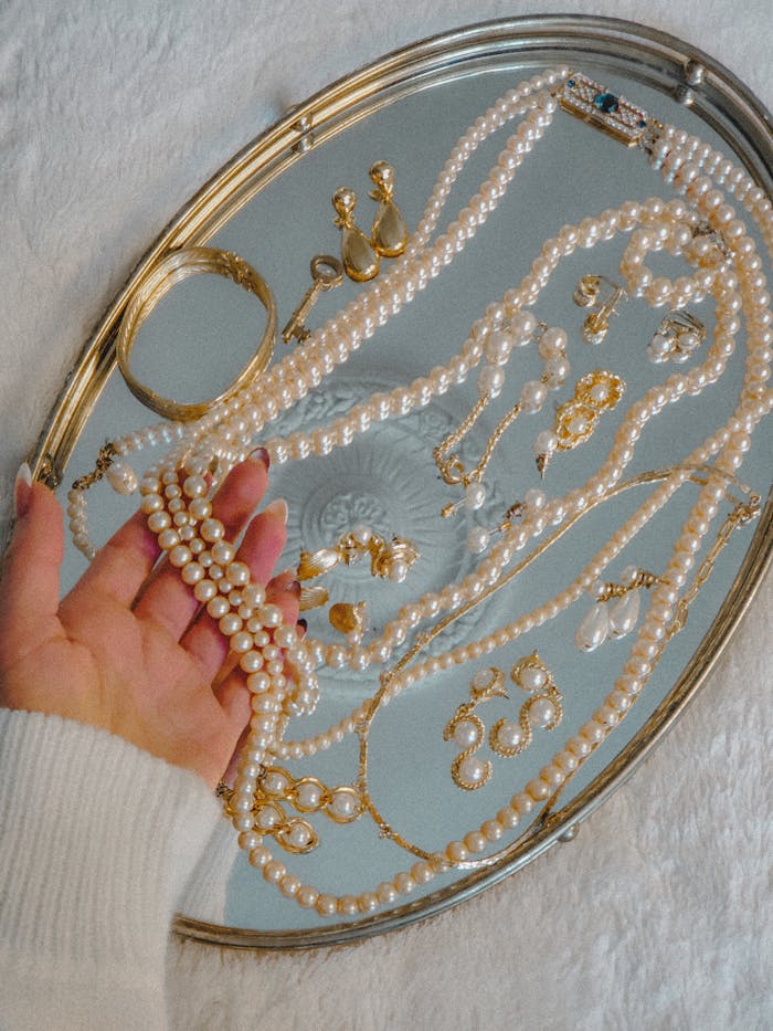 A collection of vintage pearls and gold jewelry elegantly displayed on a silver tray for a luxurious look.